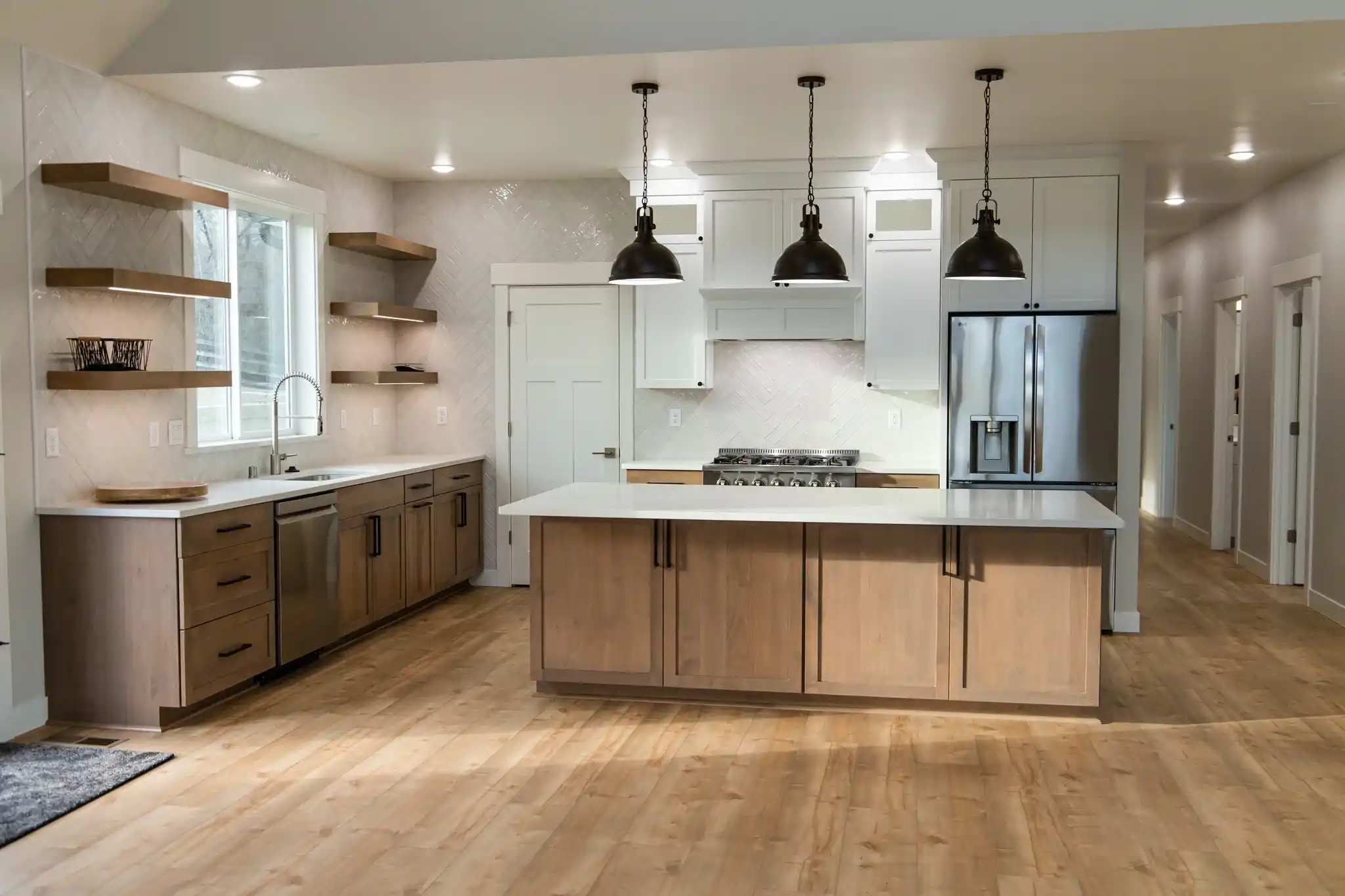 Luxury custom kitchen design by Anasazi Builders in Idaho, featuring light oak cabinetry, white quartz countertops, and industrial pendant lighting.