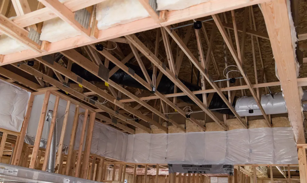 Open custom home framing with visible insulation and HVAC ductwork before drywall