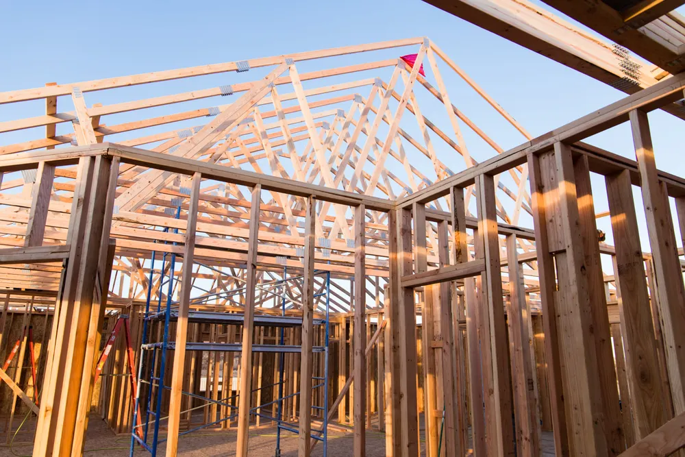 Exterior framing and roof truss installation for a new custom home in Tri-Cities by Anasazi Builders using a telehandler.