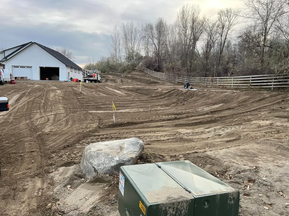 Large residential lot in West Richland under final dirt grading by Anasazi Builders, featuring a white garage building and utility boxes in the foreground