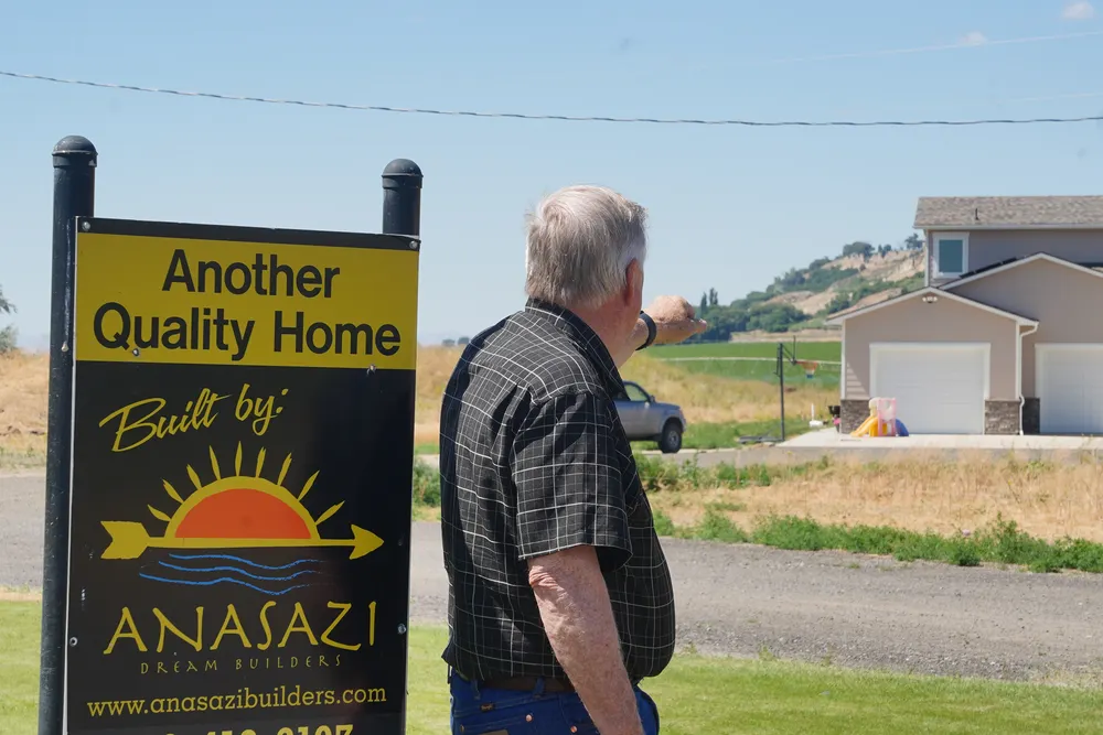 Anasazi Builders team member pointing toward a newly built Tri-Cities home