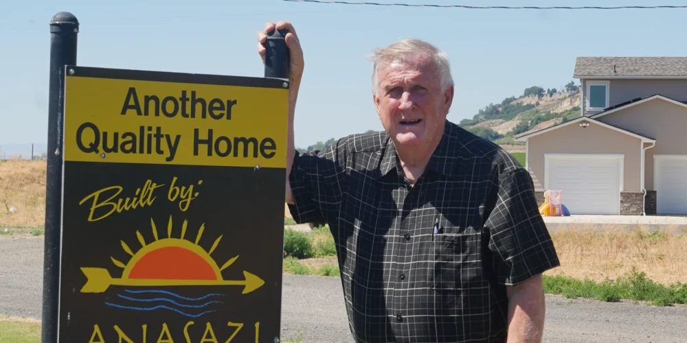 John Worlund beside an Anasazi Builders quality home sign in the Tri-Cities